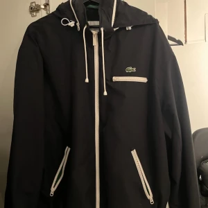 Lacoste Windbreaker - Lacoste windbreaker i storlek L, väldigt skön regnjacka som funkar i alla väder, använd fåtal gånger nypris:2000kr mitt pris:300kr priset är inte hugget i sten💸