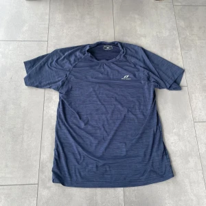 Blå träningst-shirt Pro Touch M - Sportig blå t-shirt från Pro Touch i funktionsmaterial med diskret mönster och logga på bröstet. Perfekt för träning, med korta ärmar och lätt, snabbtorkande polyester. Snygg passform och bekväm känsla för aktiva dagar.