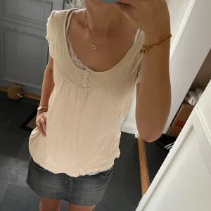 Beige finstickad topp - Beige topo med knappa från Ici et maintenant i fint skick. Står storlek 2 vilket betyder att den passar S/M. Använd gärna köp nu!
