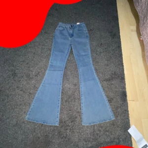 Blå bootcut jeans med utsvängda ben - Säljer ett par ljusblå jeans med riktigt breda utsvängda ben och klassisk femficksdesign. Jeansen har hög midja och är sydda i mjukt denimtyg. Perfekta för dig som vill sticka ut med en retroinspirerad look.