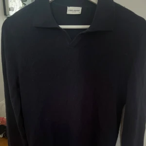 Marinblå kashmirtröja från John Henric - Snygg marinblå långärmad tröja i kashmir från John Henric. Tröjan har klassisk krage med v-ringning och en clean, stilren look. Perfekt till både jeans och kostymbyxor för en uppdaterad stil.