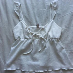 Söt linnetopp  - Supersöt vit linnetopp från Nelly med breda axelband och knyt framtill. Den är i storlek XXS men passar även XS/S! I nyskick💓