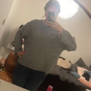 Grå stickad tröja från 157 - Mysig grå stickad tröja från 157 i storlek M. Tröjan har en loose passform och är perfekt för kyliga dagar. Den är långärmad och har en enkel, stilren design som funkar till jeans eller kjol. Materialet är mjukt och skönt mot huden.