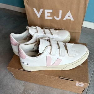 Nya Veja Recife sneakers White Petale strl  39 - Helt nyköpta Veja Recife sneakers färg White Petal. Köpte fel storlek på resa i Köpenhamn, kan ej byta därför säljer jag. Nya med kartong och kvitto. Fina detaljer med kardborreknäppning och klassiska logon i rosa. Slutsålda nästan överallt så fyndläge. Nypris i butik 1800kr. 