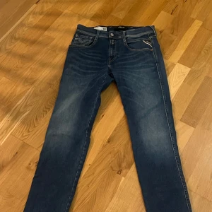 Replay Hyperflex mörkblå jeans - Säljer ett par Replay Hyperflex jeans i mörkblå tvätt med snygga slitningar. Modellen har klassisk femficksdesign, smal passform och stretchigt material som ger grym komfort. Perfekt för dig som vill ha stilrena jeans med lite edge.