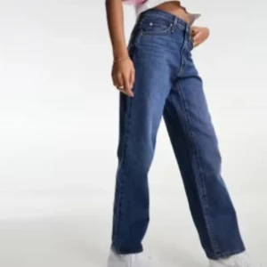 Nya Levi's Baggy jeans strl 27/33 - Säljer ett par blå jeans med hög midja och wide fit. Klassisk femficksmodell med raka ben och snygg blå tvätt. Perfekt för dig som gillar en avslappnad och trendig look. Materialet är jeans och de har knapp och dragkedja framtill.