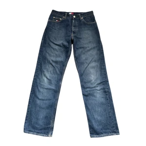 Tommy Hilfiger jeans - Snygga blå jeans från Tommy Hilfiger med klassisk femficksdesign och stort logopatch bak. Jeansen har en rak och wide passform med kontrastsömmar och ikonisk flagga på myntfickan. Perfekta för dig som gillar retrovibe och streetstyle.