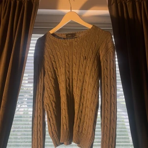 Grå kabelstickad tröja Polo Ralph Lauren - Snygg grå kabelstickad tröja från Polo Ralph Lauren i storlek L i barnstorlek (12-14år) säljer den då den blir små… funkar för båda kill och tjej. Inga defekter