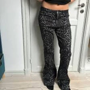 Svarta leopardmönstrade bootcutbyxor - Snygga svarta byxor med leopardmönster och bootcut passform. Byxorna har normal midja och är perfekta för dig som vill sticka ut med ett coolt mönster. Materialet känns mjukt och stretchigt för extra komfort.
