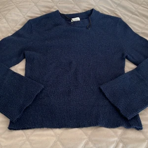 Mörkblå stickad tröja från H&M - Mysig mörkblå stickad tröja från H&M med rund halsringning och breda ribbade muddar vid ärmslut och nederkant. Funkar jättebra för vardags med jeans eller kjol. Den är använd några gånger.
