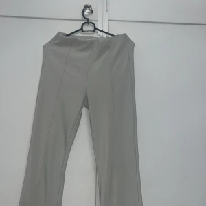 Beiga bootcut byxor från FB Sister - Snygga beiga bootcut-byxor från FB Sister med hög midja och raka sömmar framtill. Byxorna har en lätt stretchig känsla och är tillverkade i ett mjukt material som sitter skönt. Perfekta för dig som gillar en clean och stilren look.