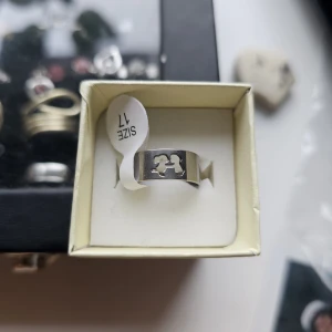 Silvrig ring med tvilling-symbol - Cool bred ring i blankt silverfärgat stål med ett utskuret tvilling-symbolmotiv. Perfekt för dig som gillar astrologi. Tillverkad i rostfritt material som håller länge.