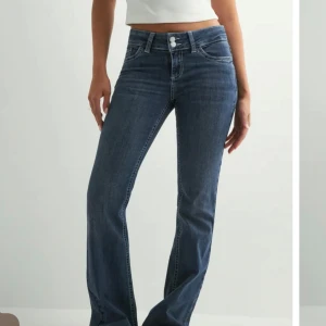 Mörkblå bootcut jeans med broderade fickor - Snygga mörkblå bootcut jeans med klassisk femficksdesign och broderade bakfickor. Perfekta för dig som gillar en tidlös men trendig look. De är helt oanvända! 