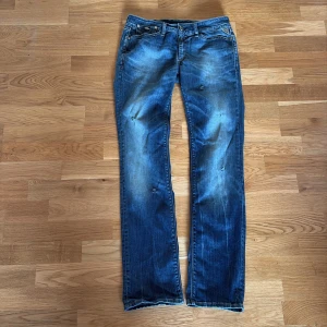 Blå jeans från JENNPEZ med slitningar - Snygga blå jeans från JENNPEZ med slitna detaljer och lätt tvättad look. Klassisk femficksmodell med raka ben och låg midja. Jeansen har coola slitningar framtill och bakfickor med dekorativa sömmar. Perfekta för en avslappnad streetstil.