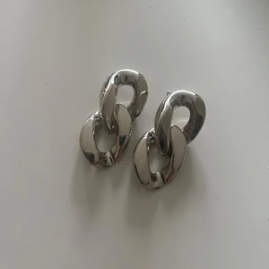 Chunky silverfärgade örhängen - Stora, chunky örhängen i silverfärg med två sammanlänkade ovala länkar. Ger en cool statement-look och passar perfekt om du vill sticka ut lite extra. Snyggt blanka och moderna.