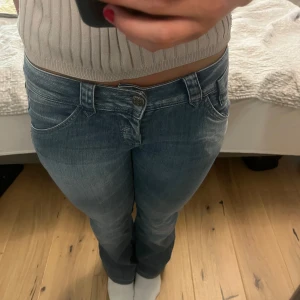 Blå bootcut jeans med låg midja - Snygga blå jeans med bootcut passform och låg midja. Jeansen är från Vero Moda och har snygga bakfickor. Midjemått 37 cm tvärs över och innerbensläng 78. 