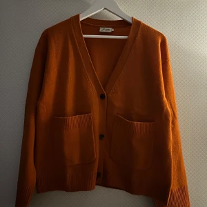 Kofta - En orange/röd kofta från Jumperfabriken i storlek S.