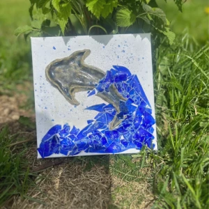 Hoppets vågor  - 🐬 “Hoppets Vågor”  En glittrande delfin bryter sig fri ur havets blå kraft – skapad av krossat glas som fångar både ljuset och rörelsen i vattnet. Den här tavlan symboliserar frihet, hopp och mod att kasta sig ut i det okända. Perfekt för havsälskaren eller som en påminnelse om att följa sitt hjärta. Handgjord av mig🩷