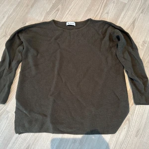 Skogsgrön stickad tröja från Wera XS/S - En enkel och stilren skogsgrön stickad tröja från Wera i storlek XS/S. Tröjan har rund halsringning och långa ärmar. Materialet består av 80% ull och 20% akryl, vilket gör den både mjuk och varm.