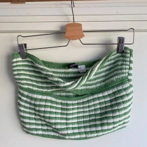 Grön och vit randig stickad tubtopp - Superfin stickad tubtopp från Gina Tricot i grönt och vitt med randigt mönster. Toppen är bandeau-modell och har en ribbad struktur som ger en snygg passform. Perfekt för varma dagar och enkel att styla med jeans eller kjol. Är storlek S men upplevs mer som M/XL. Köpt second hand och bara använd ett fåtal gånger.