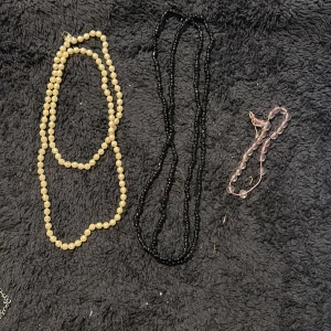 Tre pärlhalsband i olika färger - Säljer tre halsband med pärlor: ett i klassisk vit ton, ett i svart och ett i ljusrosa. Alla har rundade pärlor och enkel design, perfekta för att mixa och matcha till olika outfits. Snygga att bära var för sig eller tillsammans för en cool layering-effekt.