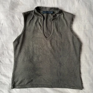 Grön ärmlös topp med ormmönster - Grön ärmlös topp från Saint Tropez med subtilt ormmönster. Den en djup v-ringning framtill och är tillverkad i ett mjukt, stretchigt material, väldigt bekväm!