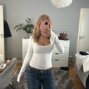 Vit långärmad topp - Säljer en vit långärmad topp med djup, rundad urringning. Tröjan från Gina Tricot och är i storlek S men jag tog bort lappen för att man skulle kunna ha den bak och fram💕💕