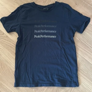 Mörkblå Peak Performance t-shirt - Mörkblå t-shirt från Peak Performance med flera tryck i olika nyanser på bröstet. Klassisk rund hals och korta ärmar. 