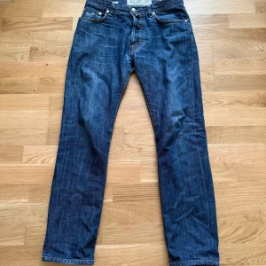 Jacob Cohen blå jeans typ 610 - Snygga blå jeans från Jacob Cohen, modell typ 610. Klassisk femficksdesign med kontrastsömmar, knappgylf och läderpatch med logga bak. Jeansen har en rak passform och är tillverkade i mjukt bomullsjeans-tyg. Perfekta för en avslappnad men stilren look.