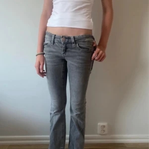 Grå bootcut jeans med detaljer - Säljer ett par lågmidjade bootcut jeans från Gina. Storlek 152. Pris kan diskuteras!