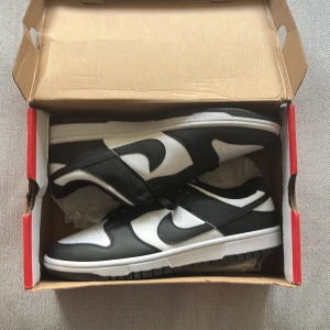 Nike Dunk Low svart/vit sneakers - Nya/ Oanvända Nike Dunk Low sneakers i svart och vitt med klassisk Swoosh på sidorna. 