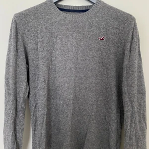 Grå stickad tröja från Hollister - Snygg grå stickad tröja från Hollister med rund halsringning. Perfekt att bära över skjorta!