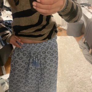 Blå långkjol med mönster och snörning - Superskön långkjol i ljusblått med mörkblått och vitt mönster. Kjolen har resår i midjan och snörning med tofsar framtill. Perfekt flowy känsla och passar till chill dagar eller när du vill känna dig extra boho.