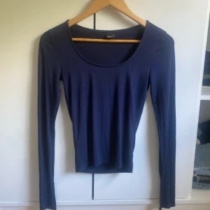 Mörkblå långärmad tröja Gina Tricot - En basic mörkblå långärmad tröja från Gina Tricot i stretchig bomull. Tröjan har rund halsringning och en slim passform som sitter snyggt på kroppen. Perfekt att styla med jeans eller kjol för en clean look.