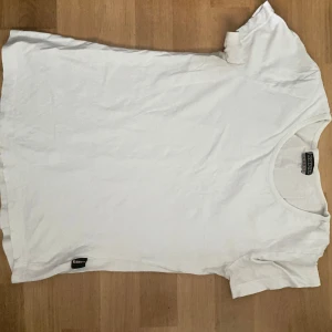 Vit t-shirt från Kappa - Klassisk vit t-shirt från Kappa i storlek Large. Enkel design med rund halsringning och diskret Kappa-logga nertill. Perfekt basic-plagg i mjuk bomull som funkar till allt.