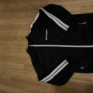 Palm Angels svart track jacket M - Svart track jacket från Palm Angels, den köptes förra året och har byxorna med ge ett förslag på båda eller köp en av dom. För mer bilder och på byxor skriv gärna😆