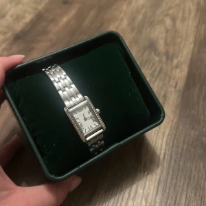 Silver klocka - Stilren klocka i silver med rektangulärt ur och romerska siffror. Har köpt en ny klocka därav säljer jag denna. Har fortfarande försäkring och kvitto kvar, samt extra länkar så skulle man vilja gå till butik och justera storlek går det. Köpte på ur och penn för runt 1100kr.🫶🏼