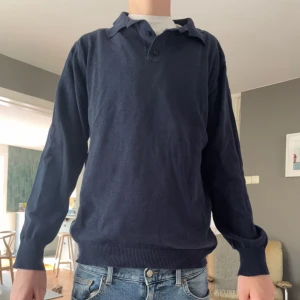 Mörkblå pikétröja med lång ärm - Klassisk mörkblå pikétröja med lång ärm och krage. Tröjan har knäppning vid halsen, den är helt oanvänd och tveka inte på att skriva om du har några funderingar.