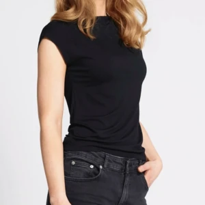 Svart ärmlös t-shirt  - En clean svart ärmlös t-shirt med rund halsringning. Sitter snyggt och har en enkel, stilren look som funkar till allt. Gjord i mjuk bomull som känns skön mot huden. Perfekt för dig som gillar minimalistisk stil.