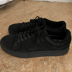 Svarta sneakers från Vagabond - Stilrena svarta sneakers från Vagabond i mocka med platt sula och rund tå. Skorna har klassisk snörning och en clean look som passar till allt. Perfekta för dig som gillar minimalistisk stil och vill ha ett par bekväma skor till vardagen.