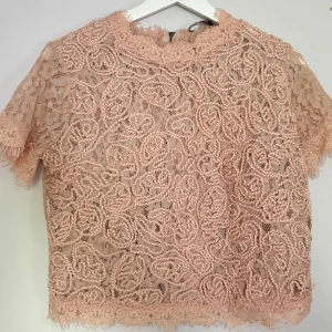 Rosa spetsblus med kort ärm - Supersöt rosa blus i spets med korta ärmar och vacker broderad struktur. 