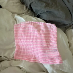 Rosa och vit randig tubtopp - Söt tubtopp i bandeau-modell med rosa och vita ränder. Toppen är ärmlös och har en mjuk, stretchig struktur som sitter bekvämt. Perfekt för varma dagar eller när du vill ha en enkel och snygg look.