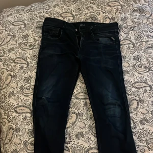 Replay Anbass hyperflex jeans mörkblå, stl 32/32 - Snygga och bekväma Replay Anbass Hyperflex jeans som tyvärr har fått litet större hål på ena benet,  Det finns också ett litet hål i grenen som knappt syns och inte påverkar komforten eller passformen.  Jeansen är mörkblå/svarta med stretch för extra rörelsefrihet och passar både till vardags och fest.