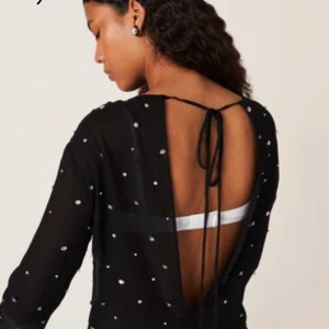 Topp Zara - Svart topp, öppen rygg och knytband i nacken. Lätt transparent tyg och långärmad modell som ger en cool och trendig vibe. Perfekt för dig som vill sticka ut med snygga detaljer. Använd 1 gång.