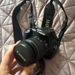 Canon eos 1100D - 	Inkluderar: Batteri, laddare och objektivlock  Skick: Kameran är i fint begagnat skick. Allt fungerar som det ska,  inga repor på lins eller skärm. Har använts sparsamt på senare tid och förtjänar att användas mer.  Perfekt för nybörjare eller som rese-/extrakamera!