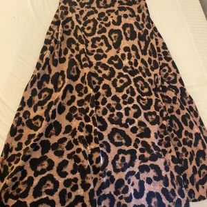 Leopardmönstrad kjol - Säljer en maxad kjol med leopardmönster i beige och svart. Kjolen har en snygg dragkedja i sidan för enkel påklädning och ett flowy fall. Perfekt för dig som vill sticka ut med ett djurmönster och cool vibe.