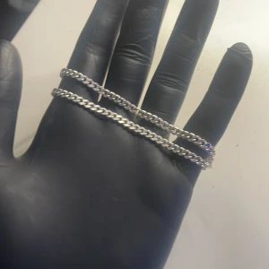 Kedjehalsband i silverfärg - Stilrent halsband med klassisk kedjelänk i silverfärg. Kedjan har en robust karbinhake som lås och passar perfekt för dig som gillar en clean och tidlös look. Länkarna är platta och blanka vilket ger ett snyggt skimmer.