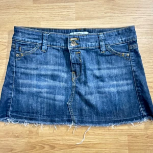 Jeanskjol  - Snygg jeanskjol från Yeans Please i klassisk blå denim. Kjolen har en kort längd med fransig nederkant och femficksdesign. Perfekt för en avslappnad stil.