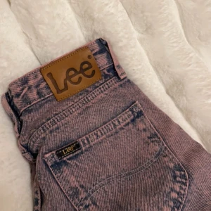 Rosa jeansbyxor från Lee - Snygga rosa jeansbyxor från Lee med en unik tvättad look. Byxorna har en klassisk femficksdesign och hög midja. Perfekta för att ge din outfit en färgklick!💓