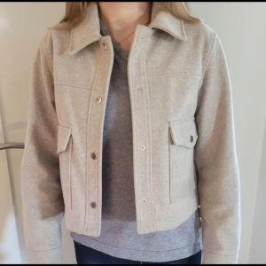 Beige jacka från Zara - Snygg beige jacka från Zara med krage och knappar framtill. Jackan har en croppad design och två fickor med knappar. Perfekt för en stilren look. Säljer för den är för liten 🥰